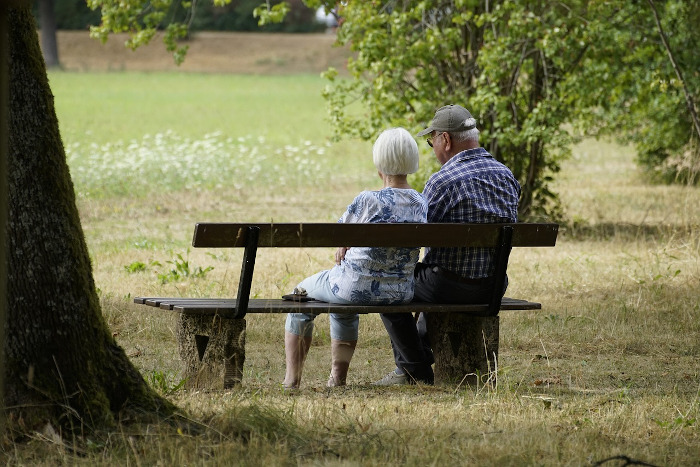 elderly couple sitting on a park bench in a garden