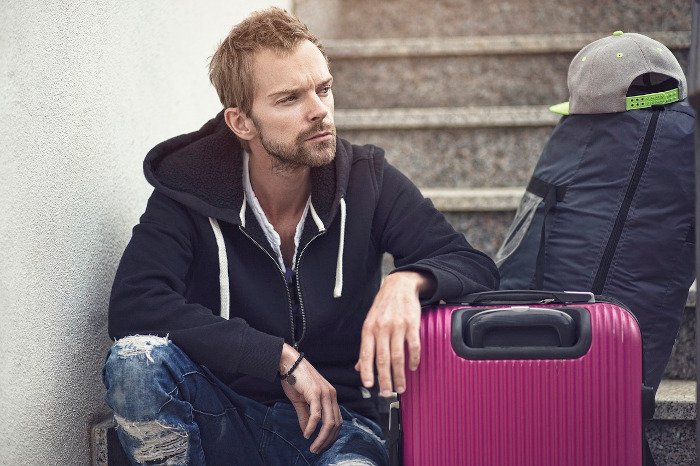 man sitting on stairs with his belongings