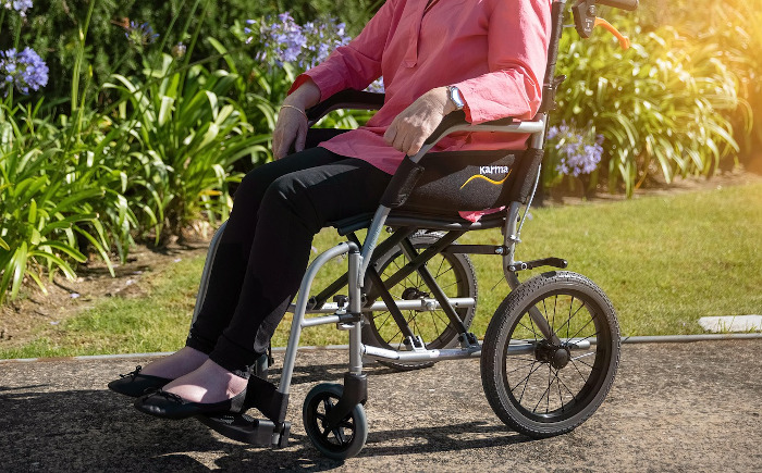 woman in pink shirt sitting a wheelchair in a garden