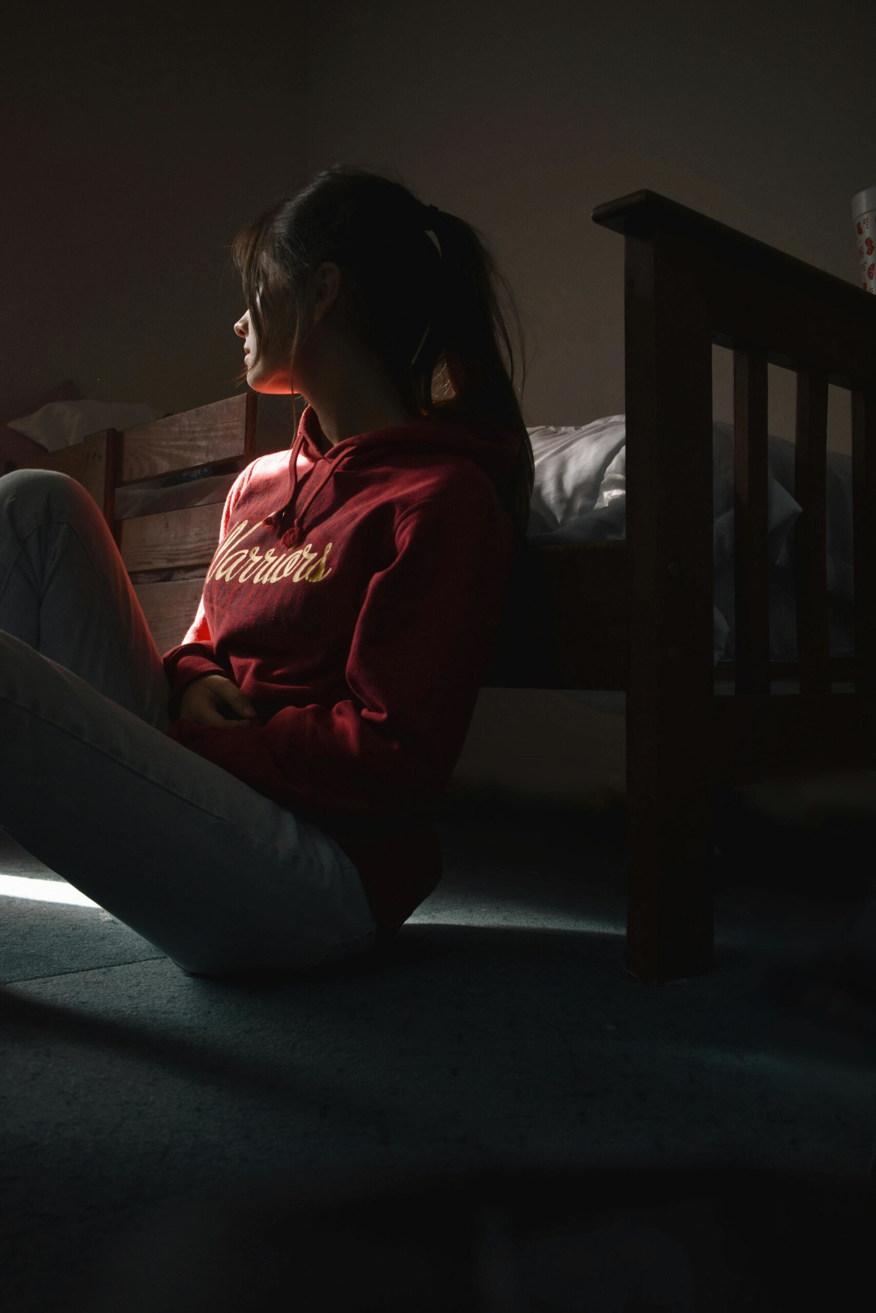 young woman sitting in a dark bedroom